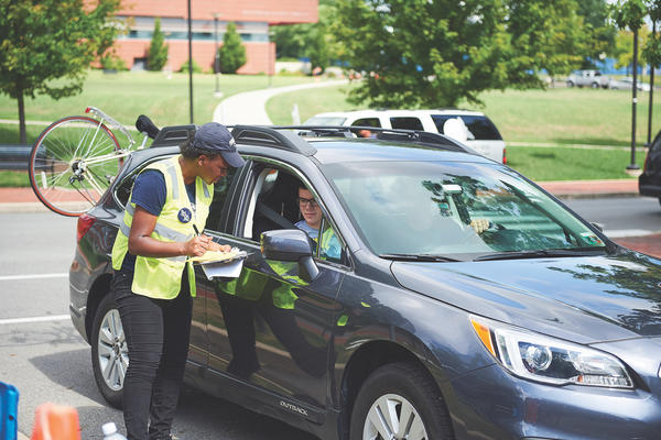 Employee assisting with parking for student arrival. 